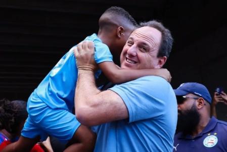 Rogério Ceni, técnico do Bahia, carrega criança que acompanhava embarque da delegação