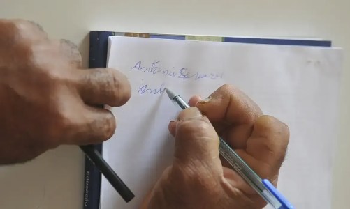 mão de uma pessoa idosa escrevendo com dificuldade em um papel