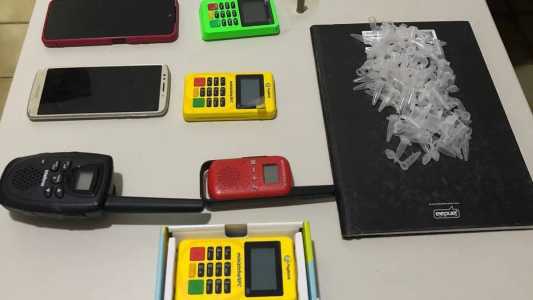 Foram apreendidos pinos de cocaína, celulares, cartuchos de arma de fogo e máquinas de cartão de crédito