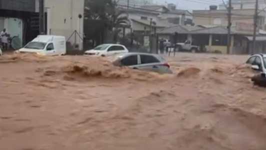 Foto mostra carro sendo levado pela enchente em Itaúna
