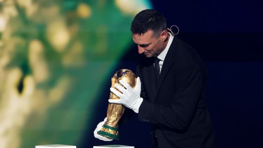 Lionel Scaloni, técnico da Argentina, usa luvas ao segurar taça da Copa do Mundo