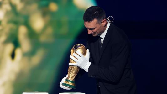 Lionel Scaloni, técnico da Argentina, usa luvas ao segurar taça da Copa do Mundo
