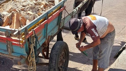 Gera arruma o chinelo de dedo enquanto troca do pneu da carroça