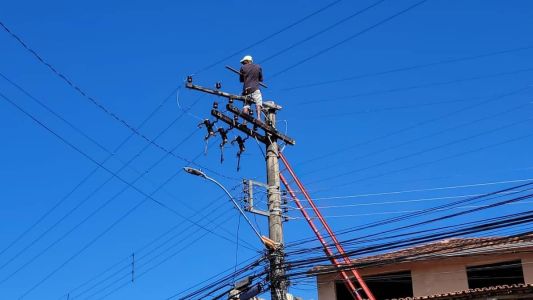 Homem usa um pedaço de madeira para impedir que bombeiros subam no poste