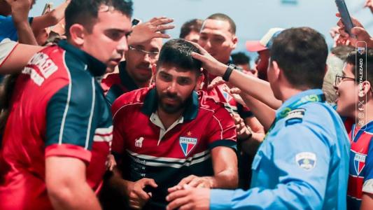 Jogadores do Fortaleza passam por multidão para embarcar a São Paulo, na noite do domingo (24)