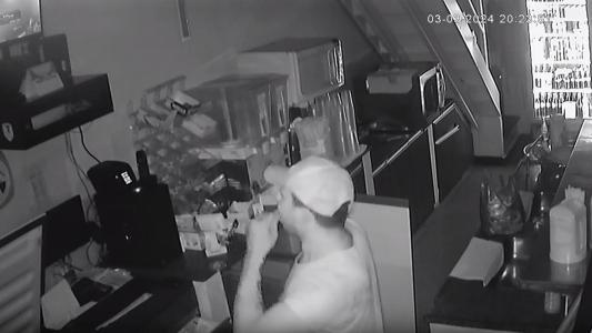 Foto mostra ladrão colocando chiclete na boca enquanto se olha pela tela da câmera de segurança em Governador Valadares (MG)
