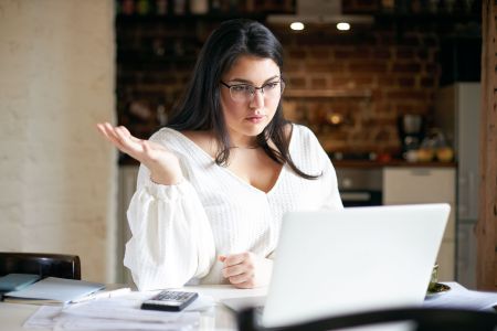 Jovem com expressão de dúvida em frente a tela de computador