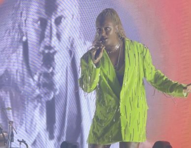 cantora liniker com roupa verde segurando microfone no palco