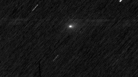 Um fundo espacial preto com listras brancas e um único ponto branco difuso. As listras são estrelas e o ponto é o cometa 3I/ATLAS.