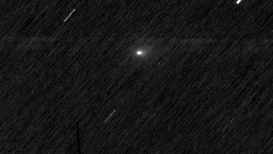 Um fundo espacial preto com listras brancas e um único ponto branco difuso. As listras são estrelas e o ponto é o cometa 3I/ATLAS.