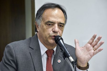 Na imagem, Mauro Tramonte. Ele é um homem branco, de cabelo cinza/branco. Ele usa terno cinza e gravata vermelha com listas brancas.
