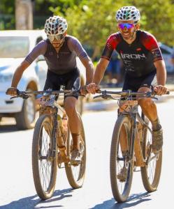 Imagem mostra dois ciclistas de montain bike pedalando durante prova em Montes Claros