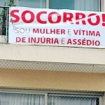 Mulher pendura faixa em prédio, pede socorro e revela ser espionada por vizinho há 2 anos