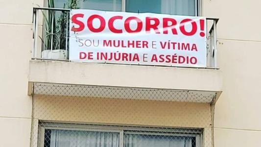 Mulher pendura faixa em prédio e pede ajuda