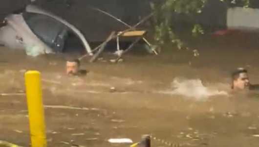 Foto mostra homens flagrados nadando contra enchente na avenida Prudente de Morais, em BH