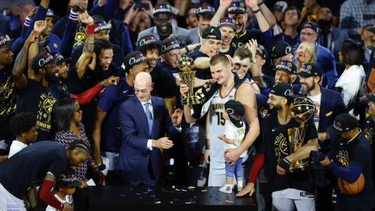 Nikola Jokic, pivô sérvio do Denver Nuggets, cercado pelos companheiros e pelo comissário da NBA, Adam Silver, após conquistar a liga