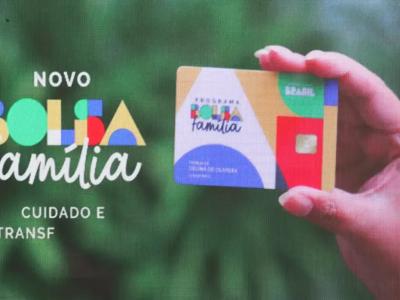 Mão feminina segurando o cartão do Bolsa Família