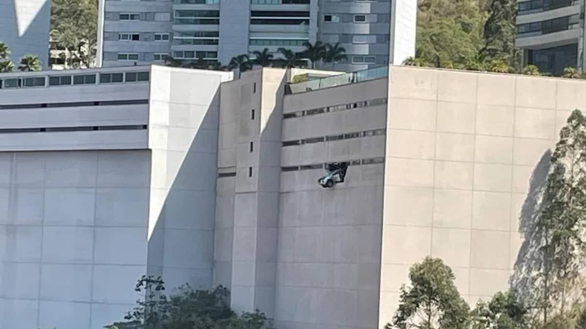Carro 'abre buraco' em parede e fica pendurado em prédio na Grande BH