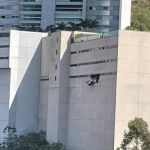 Carro 'abre buraco' em parede e fica pendurado em prédio na Grande BH