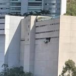 Carro 'abre buraco' em parede e fica pendurado em prédio na Grande BH