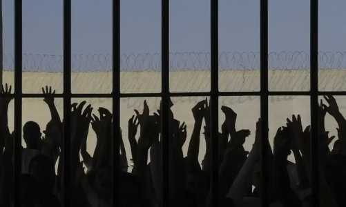 Detentos na penumbra em uma cela