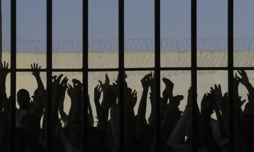 Detentos na penumbra em uma cela