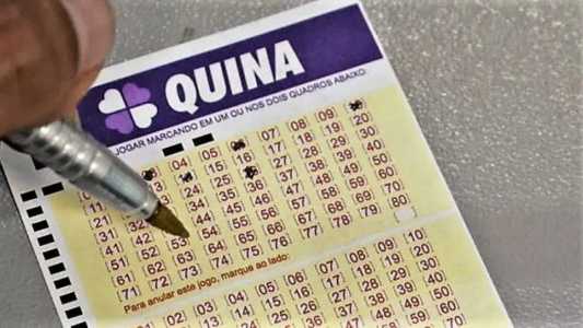 Uma mão segura uma caneta e prencheendo um volante da Quina