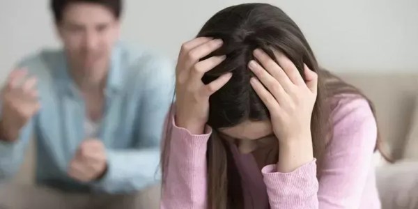 Mulher, vestida de rosa, sendo abusada psicologicamente por um homem, com camisa social azul