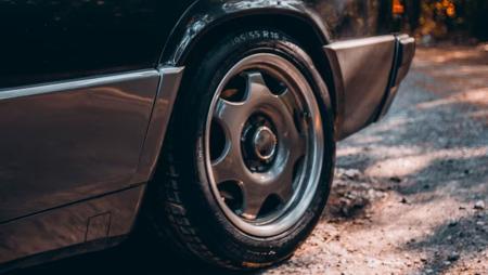 Foto mostra roda de carro preto em cima de um terreno arenoso