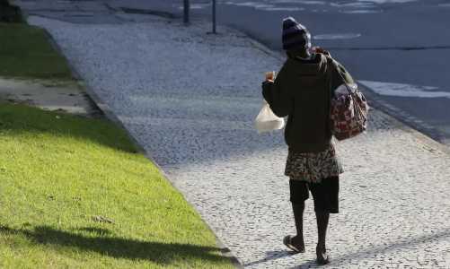 Morador em situação de rua caminhando em calçada