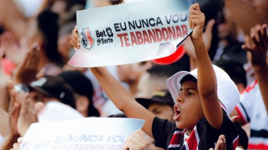 Garoto torcedor do Santa Cruz segura faixa com a frase: "Eu nunca vou te abandonar"