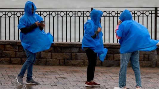 Trio tenta se proteger dos ventos, que chegam a 100 km/h