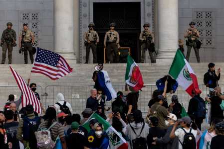 Delegados do xerife montam guarda enquanto manifestantes se reúnem nos degraus da Prefeitura, enquanto os protestos continuam em resposta às operações federais de imigração em Los Angeles.