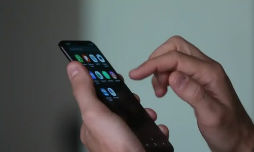 Imagem de uma mão mexendo em um telefone celular