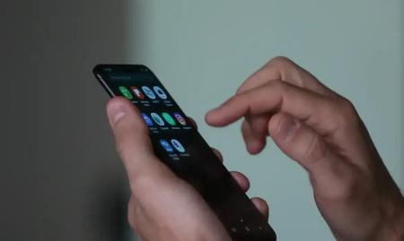 Imagem de uma mão mexendo em um telefone celular