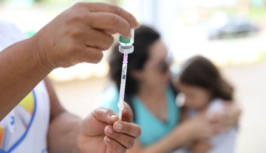 Foto mostra profissional de saúde se preparando para aplicar vacina em criança em Belo Horizonte