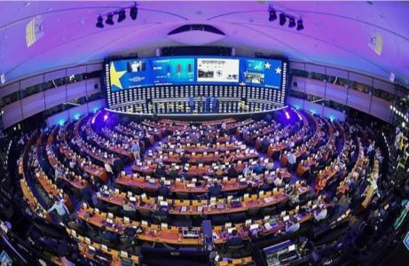 Parlamento Europeu com pessoas sentadas ao redor de uma tela grande