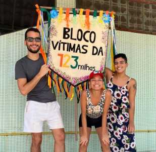Criadores do bloco aparecem com estandarte escrito: "Bloco Vítimas da 123milhas"