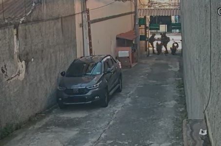 imagem de câmera de segurança mostra um beco com carro estacionado e duas pessoas cometendo assalto a um motociclista