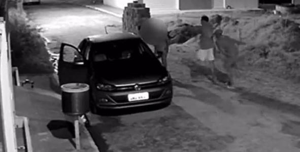 Dois homens armados abordando um homem durante um assalto de um carro