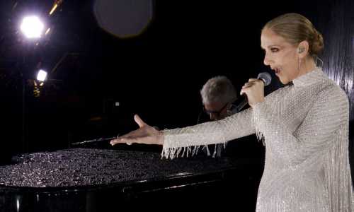 Celine Dion de vestido branco brilhante se apresentando nas Olimpíadas de Paris de 2024. No fundo, um homem tocando um piano de cauda preto.