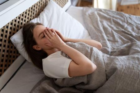 Mulher deitada na cama com o sono agitado