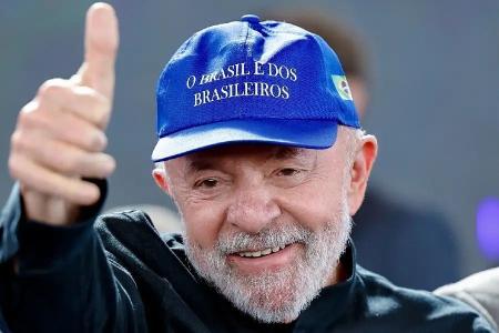 O presidente Luiz Inácio Lula da Silva acena para o público enquanto veste um boné azul com os dizeres "O Brasil é dos brasileiros"
