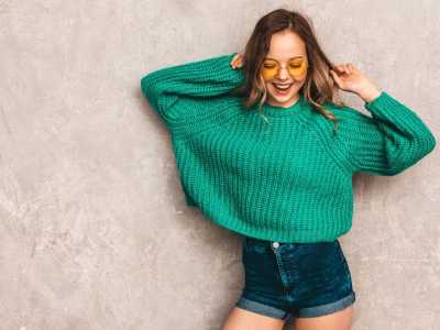 Mulher sorridente usando uma blusa verde e shorts jeans