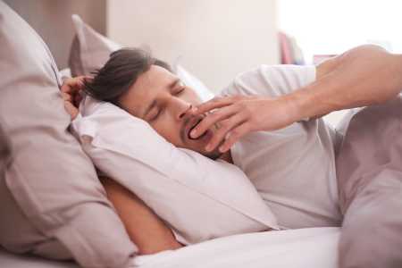 Homem bocejando na cama