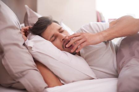 Homem bocejando na cama