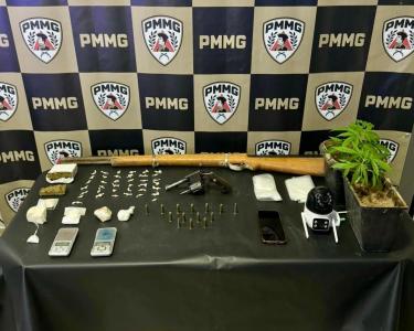 A PM apreendeu drogas, armas, munições, balanças, pés de maconha, embalagens, câmera e celular do suspeito.