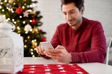 Homem mexendo no celular durante o Natal