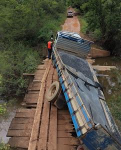 A carroceria do caminhão ficou parcialmente inclinada para dentro do rio, agravando a situação e os riscos no local.