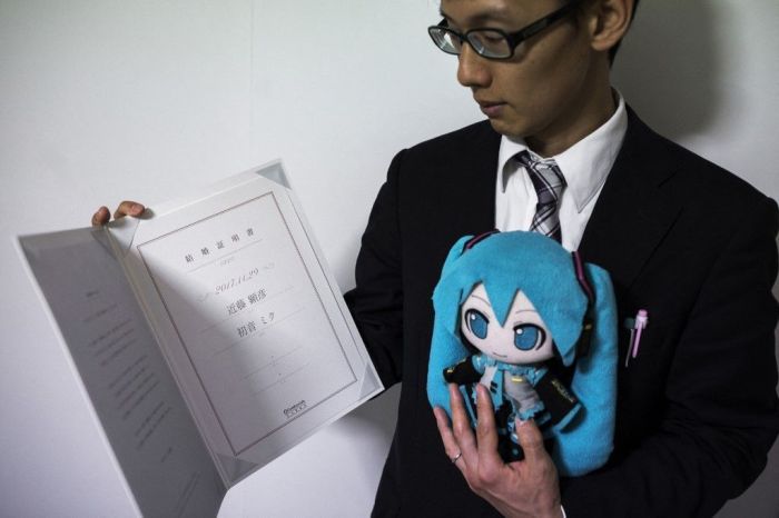 Nesta fotografia tirada em 10 de novembro de 2018, o japonês Akihiko Kondo posa com uma boneca da cantora japonesa de realidade virtual Hatsune Miku, enquanto mostra a certidão de casamento deles, em seu apartamento em Tóquio, uma semana depois de se casar com ela. Nesta fotografia tirada em 10 de novembro de 2018, o japonês Akihiko Kondo posa com uma boneca da cantora japonesa de realidade virtual Hatsune Miku, enquanto mostra a certidão de casamento deles, em seu apartamento em Tóquio, uma semana depois de se casar com ela.
